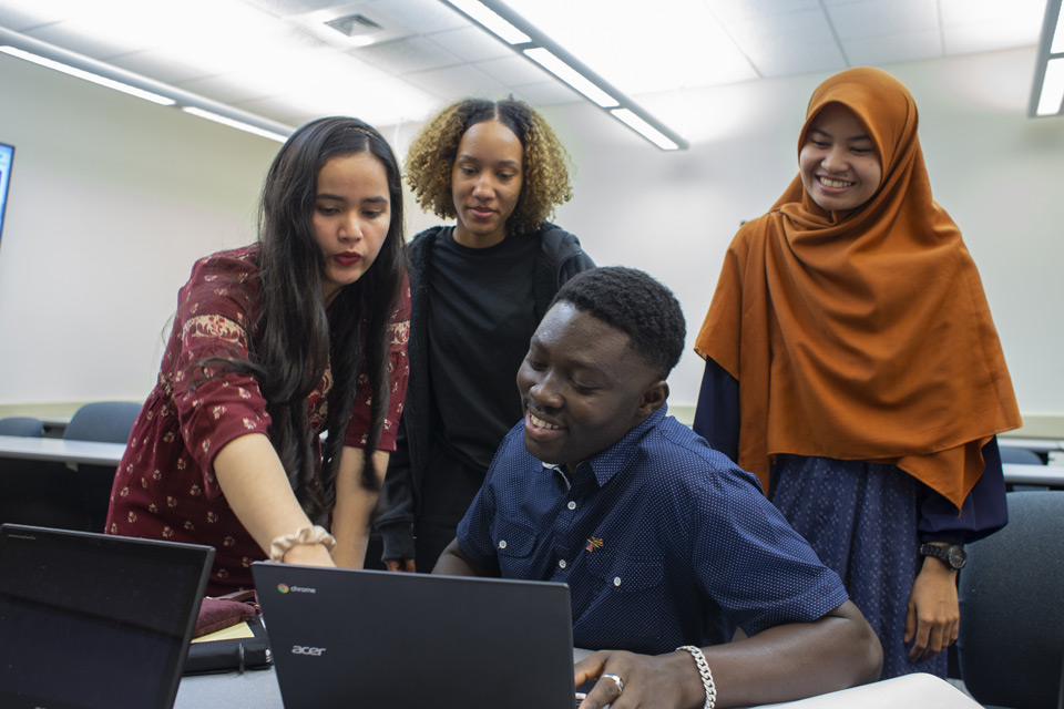 students sitting around a computer in classroom
