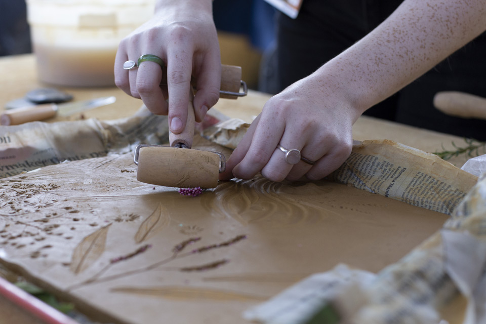 Student rolling patterns into clay