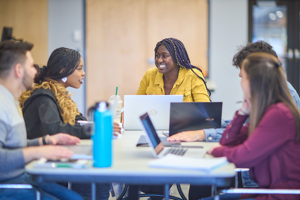 Five diverse students sitting at a table