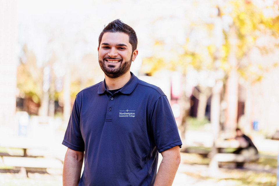 Man in Northampton Community College polo smiling on campus